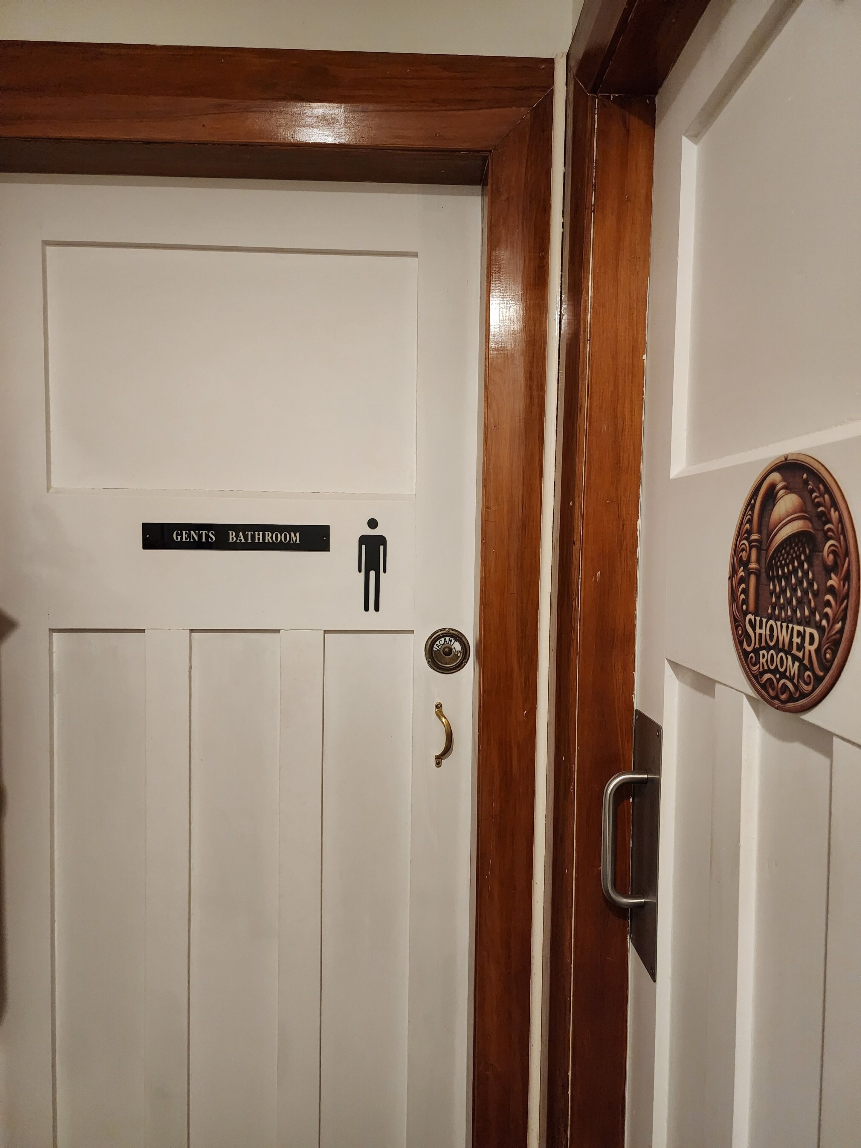 Una puerta con un cartel que indica un baño de hombres y un cuarto de ducha.