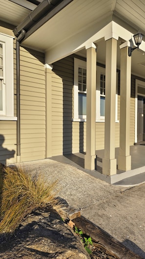 A building with a covered porch, a window, and a lamp post.