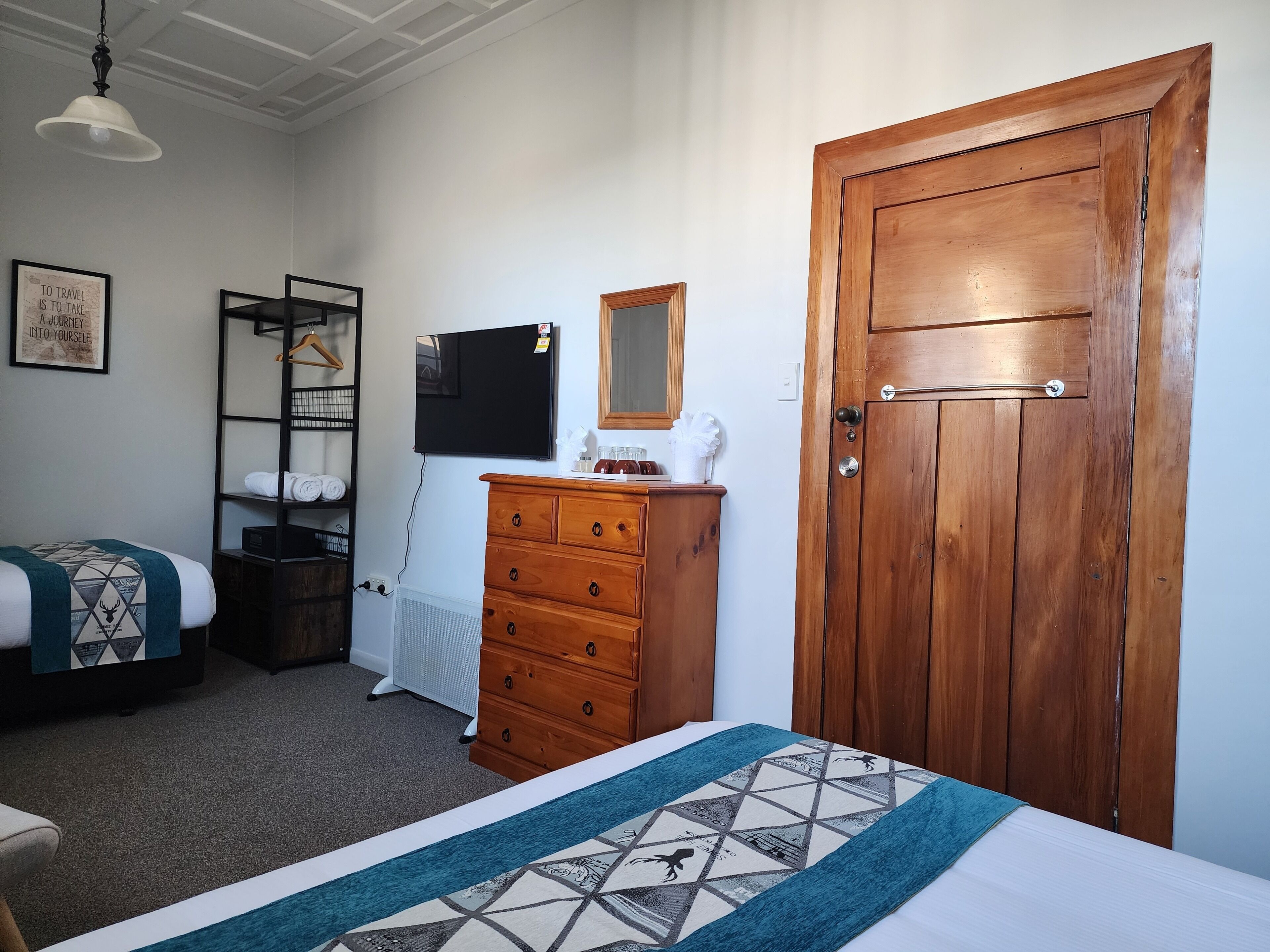 Een slaapkamer met een bed, een kapstok, een kledingkast en een televisietoestel.