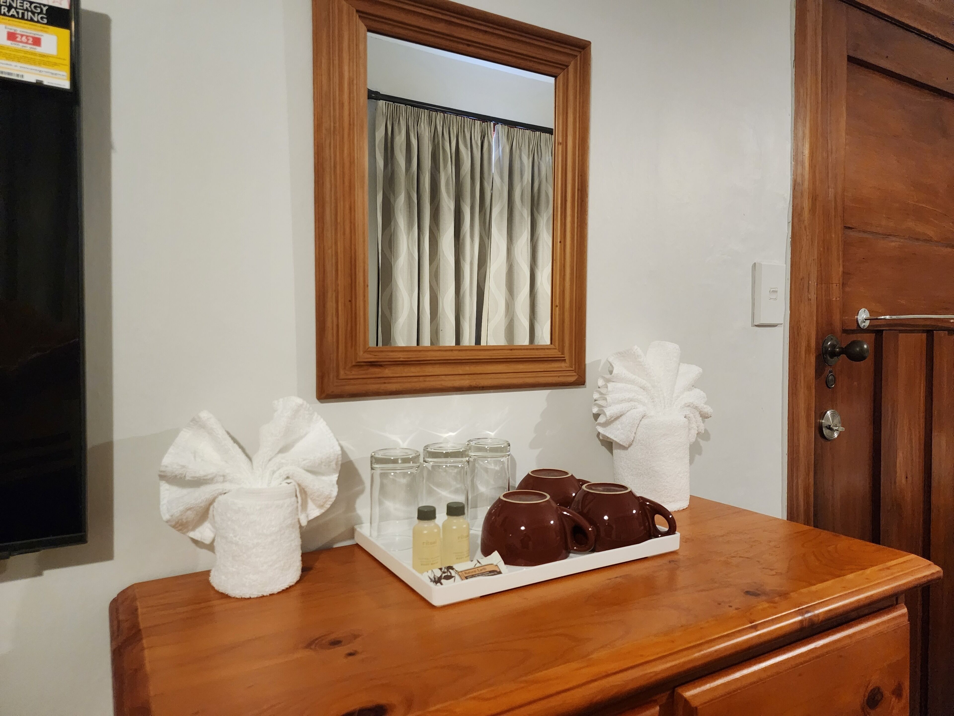A wooden dresser with a mirror, a tray with toiletries, and a towel.