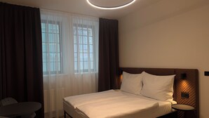 A modern hotel room with a bed, a round table, and a chair. - Factory Suites (Prague)