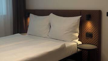 Habitación de hotel con cama, una mesita redonda y cabecera con iluminación integrada.