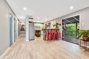 A spacious kitchen with a dining area, a refrigerator, and a balcony with a view. - Salty Kisses Apartment. Across the road from the beach. (Marcoola)