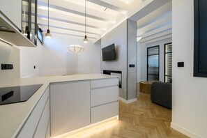 A modern kitchen with a built-in island, pendant lighting, and a flat-screen TV mounted on the wall. - 2BR 2BA | Almagro Residence | Quiet Luxury Stay (Madrid)