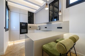 A modern kitchen with a central island, built-in appliances, and pendant lighting. - 2BR 2BA | Almagro Residence | Quiet Luxury Stay (Madrid)