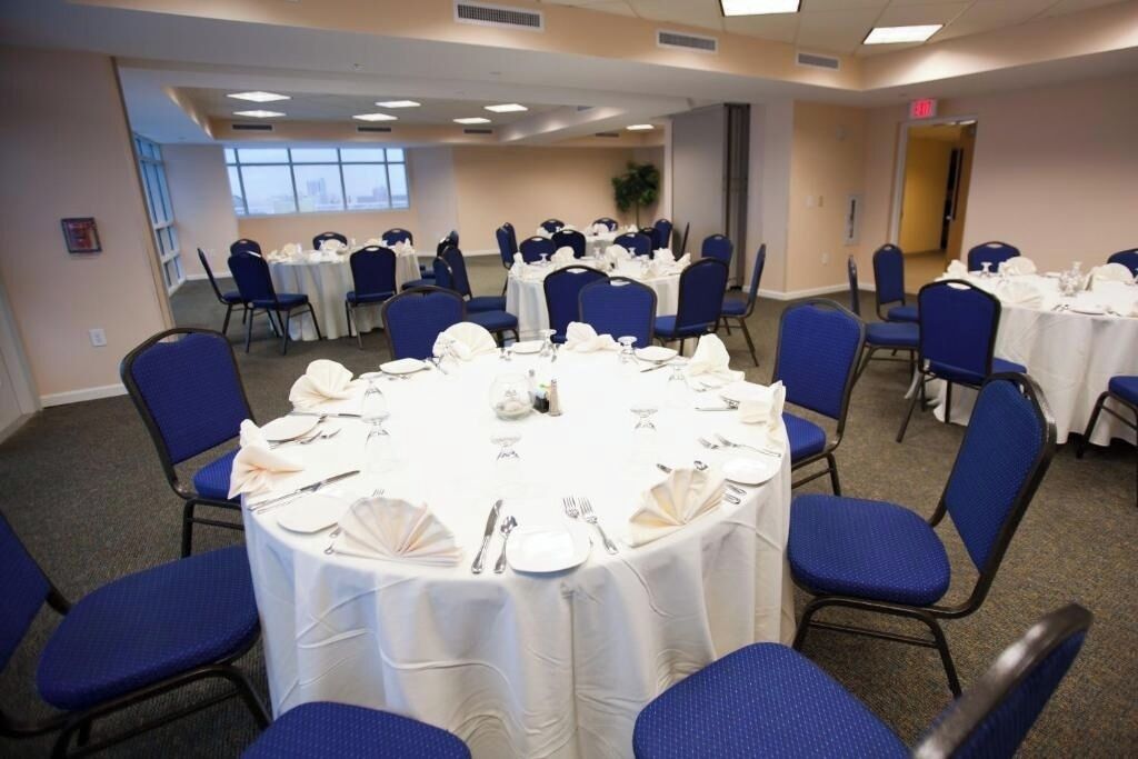 A conference room with round tables, blue chairs, and white tablecloths.