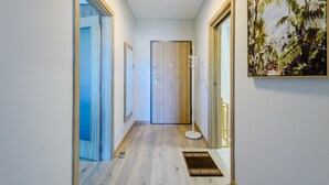 A hallway with a wooden floor, a door at the end, and a painting on the wall. - Azul View Praia da Rocha (Portimão)
