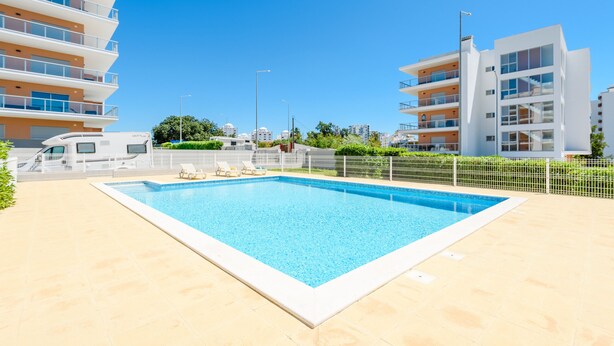 A swimming pool with lounge chairs, surrounded by modern buildings and a clear sky. - Azul View Praia da Rocha (Portimão)
