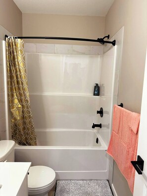 A bathroom with a shower, toilet, and sink.