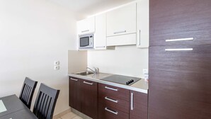 Una cocina compacta con microondas, lavabo y armarios.