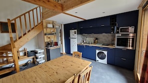 A compact kitchen with a wooden dining table, built-in appliances, and a laundry machine. - Charming apartment for 8 people, with a balcony and mountain views (Saint-Sorlin-d´Arves)