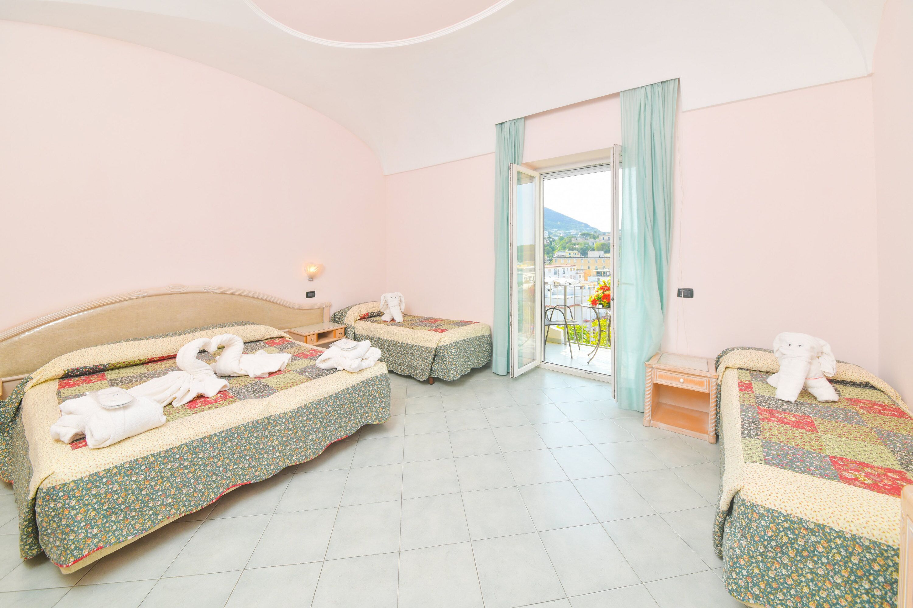 A hotel room with two beds, a balcony with a view, and a small table.