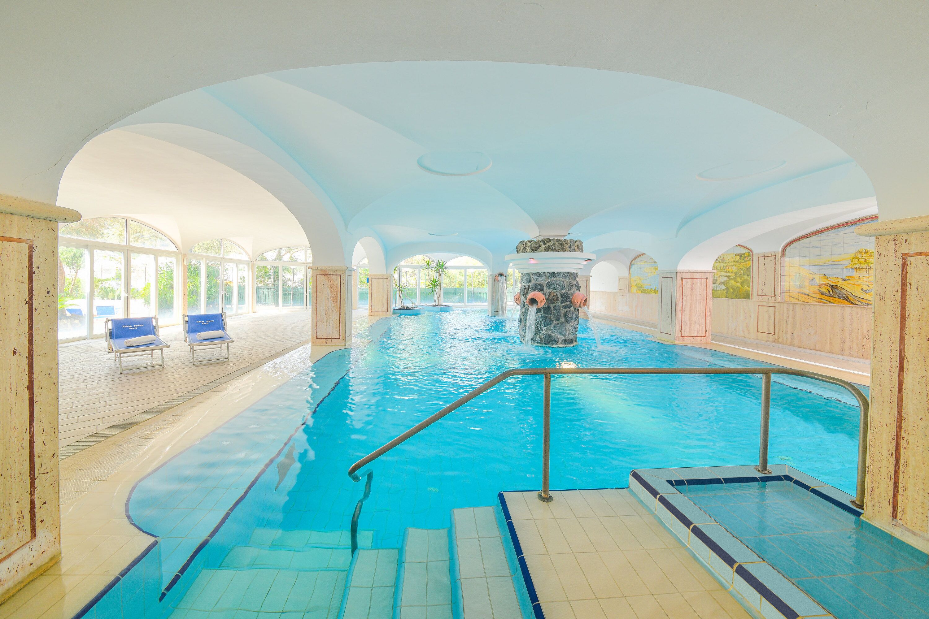 Una piscina techada, una piscina al aire libre, sombrillas