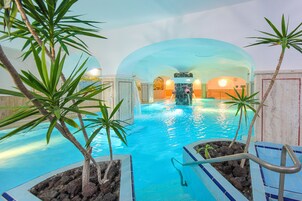 Una piscina techada, una piscina al aire libre, sombrillas