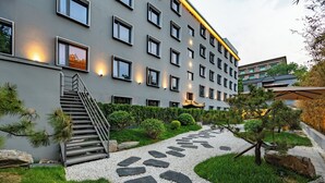 Moderni rakennus, jossa on portaikko, kivipolku ja viheralueita.