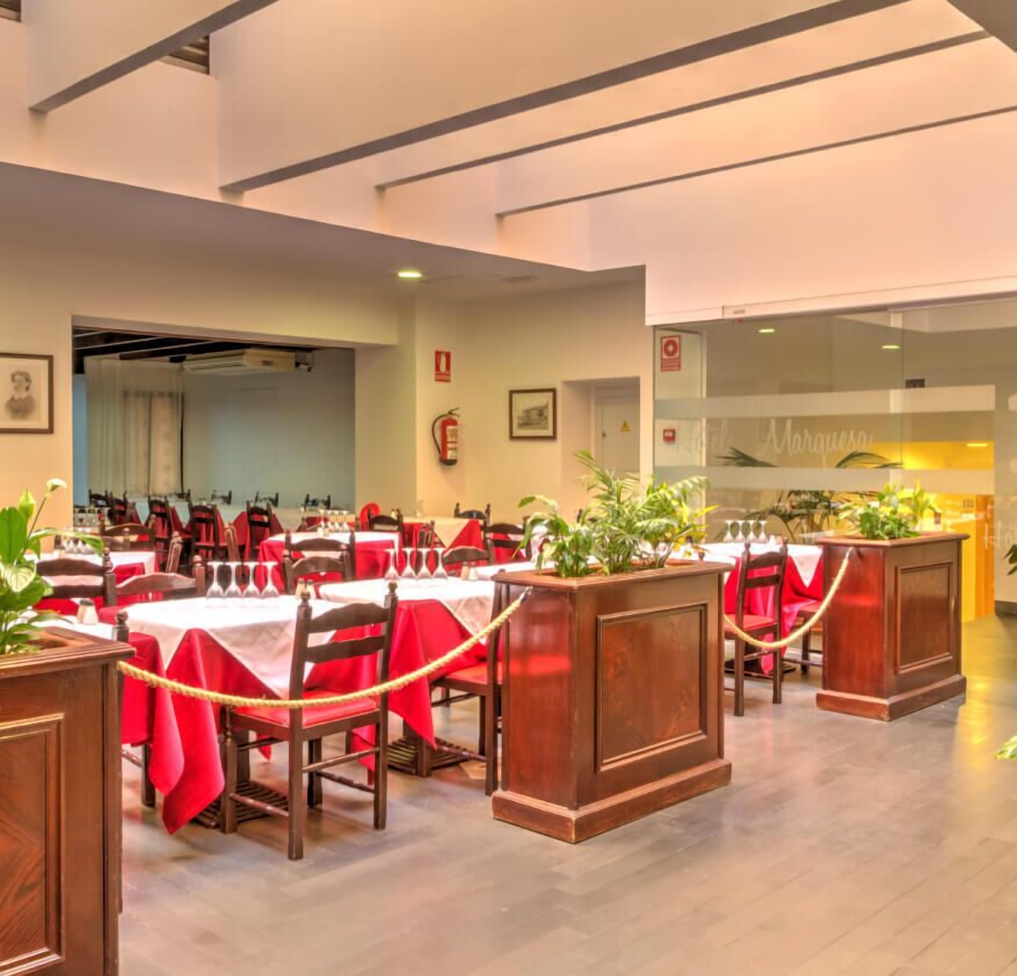 Un restaurante con varias mesas, manteles rojos y sillas de madera.