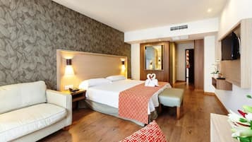 Una habitación de hotel con una cama, un sofá, una mesita de noche, un espejo y un televisor.