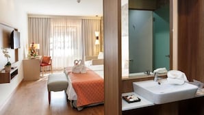 Une chambre d’hôtel avec un lit, une table de chevet, un miroir, un lavabo et une douche.