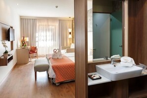 Una habitación de hotel con cama, mesita de noche, espejo, lavabo y ducha.