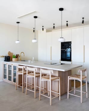 A modern kitchen with a central island, bar stools, pendant lighting, and built-in appliances. - 27th Top Floor Designer Apartment In Mercury Tower (Saint Julian's)