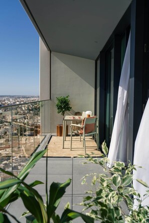 Un balcón con una mesa, sillas, una planta en maceta y vistas a la ciudad.