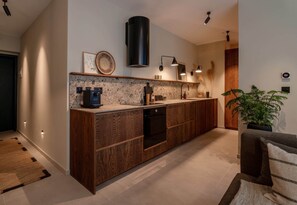 A modern kitchen with a wood finish, built-in appliances, and pendant lighting. - Designer Luxury Apartment in Mercury Tower (Saint Julian's)