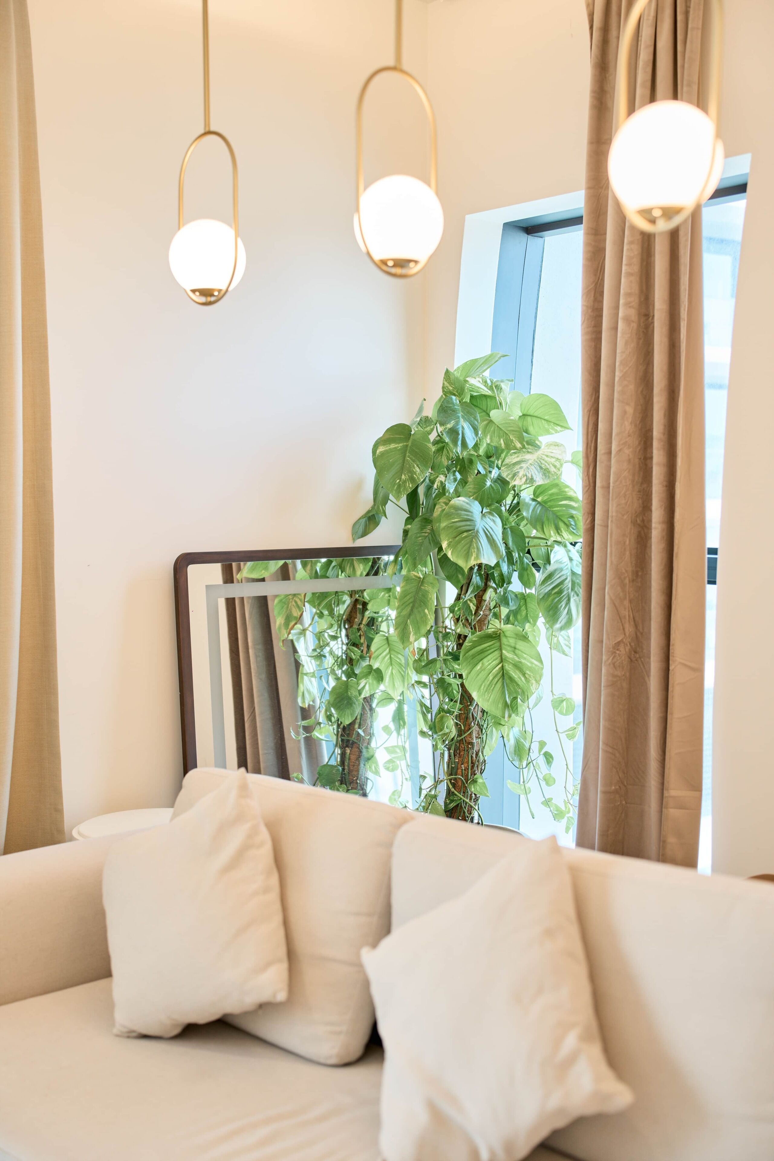 Een slaapkamer met een bed, kussens, een spiegel en een plant.