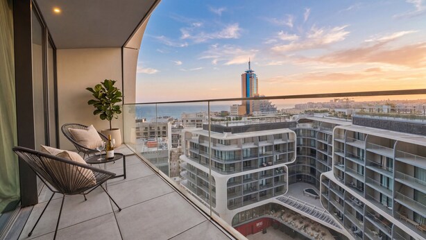 Een balkon met uitzicht op een modern gebouw en een verre toren.