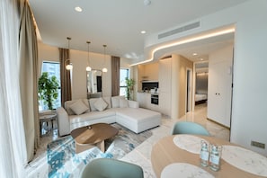 A modern living room with a sectional sofa, a dining table, and a kitchen area. - Seaview Mercury Tower Apartment With Rooftop Pool (Saint Julian's)