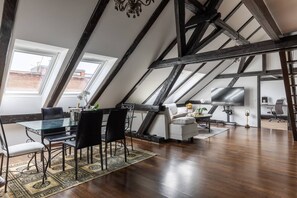 Ein Loft-Zimmer mit Essbereich, einer Couch, einem Fernseher und einer Treppe.