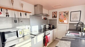 A modern kitchen with stainless steel appliances, a built-in oven, and a countertop with a kettle. - Modern 2BR Home w/Driveway | Sleeps 6 (Lincoln)