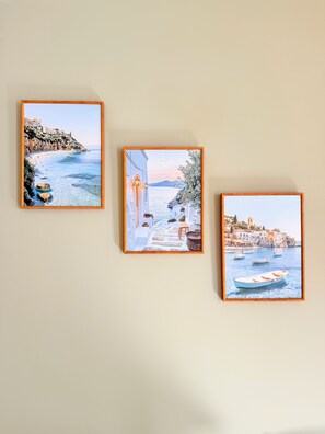 Tres cuadros con paisajes costeros en una pared.