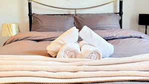 A bed with a headboard, a set of towels, and three framed pictures on the wall. - Modern 2BR Home w/Driveway | Sleeps 6 (Lincoln)