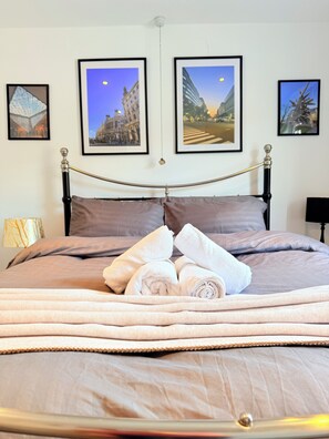 Una cama con cabecera, un juego de toallas y tres cuadros en la pared.