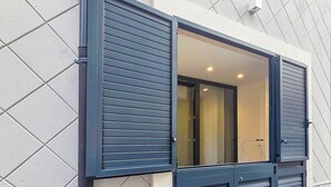 A modern building with a geometric tiled facade, a large window with horizontal blinds, and a visible door. - Blue Pearl - Grey Pearl Suites (Manfredonia)