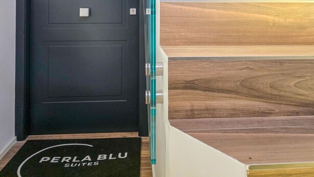 A staircase with wooden steps and a black door with a glass panel. - Blue Pearl - Grey Pearl Suites (Manfredonia)