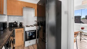 A kitchen with wooden cabinets, a black refrigerator, a stove, and a dishwasher. - The Lookout Newhaven (Newhaven)