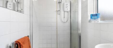 A shower with a glass door, a white sink, and a towel rack with a towel.