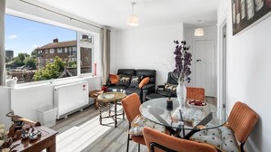 A modern living room with a glass dining table, comfortable seating, a fireplace, and a view of the city. - The Lookout Newhaven (Newhaven)