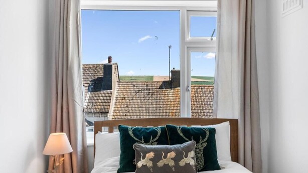 A bedroom with a bed, pillows, a nightstand, and a window with curtains. - The Lookout Newhaven (Newhaven)