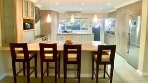 A modern kitchen with a central island, pendant lighting, and built-in appliances. - Hout Bay Gem 61 Milner  (Cape Town)
