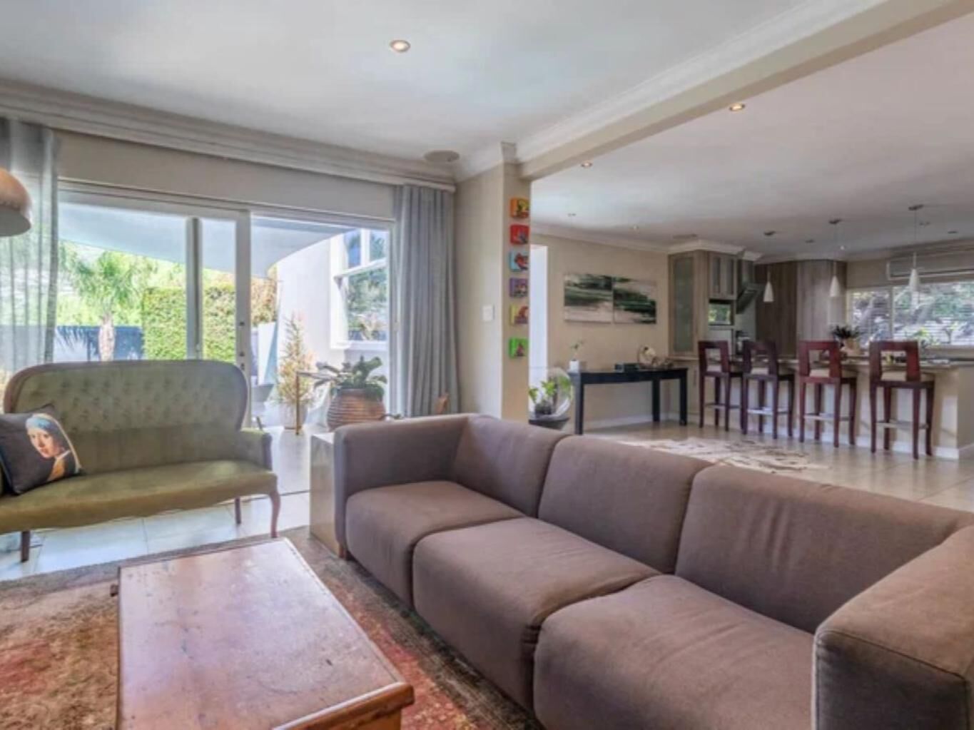 A spacious living area with a sofa, a coffee table, and a dining area with chairs and a table.