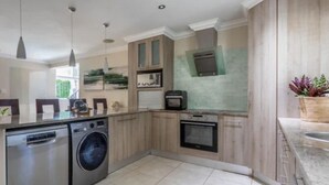 A modern kitchen with stainless steel appliances, wooden cabinets, and a built-in oven. - Hout Bay Gem 61 Milner  (Cape Town)