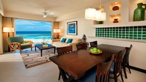 A hotel room with a view of the ocean, a dining area with a wooden table, and a kitchen with green tiles. - Ocean-View 2BR Villa at Westin Lagunamar – Cancún Beachfront Pools & Spa (Cancún)