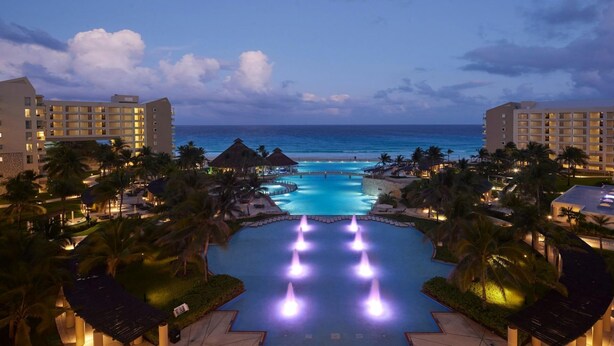 A resort with a large pool, palm trees, and a view of the ocean. - Ocean-View 2BR Villa at Westin Lagunamar – Cancún Beachfront Pools & Spa (Cancún)