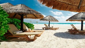A beach with lounge chairs and thatched umbrellas. - Ocean-View 2BR Villa at Westin Lagunamar – Cancún Beachfront Pools & Spa (Cancún)