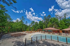 A pool area with a fenced deck, lounge chairs, and a covered seating area. - 3-bedroom riverside condo in serene Wisconsin Dells 10-14 guests (Wisconsin Dells)