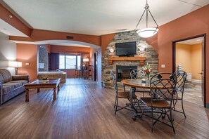 A spacious living room with a fireplace, a dining area with a round table and chairs, and a sofa. - 3-bedroom riverside condo in serene Wisconsin Dells 10-14 guests (Wisconsin Dells)