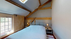 A bedroom with a bed, two bedside tables, a window, and wooden beams. - STRING (Sainte-Foy-de-Longas)