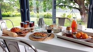 A breakfast table with bread, pastries, jams, tea, and juice.